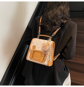 Détail du sac à dos vintage avec motif monogramme d'élan et breloque ours en peluche