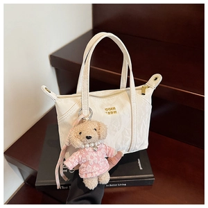 Vue détaillée d'un mini sac cabas blanc plissé avec une breloque en peluche de caniche