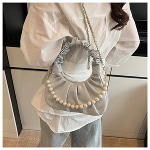 Detail of light blue cloud bag featuring large faux pearls and ruched handle texture