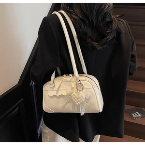 Détail du sac Boston crème avec pendentif cœur en perles et garniture en dentelle fine
