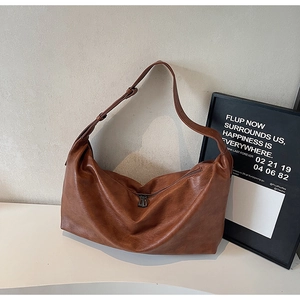 Detailed close-up of brown oiled leather shoulder bag with vintage texture and dual zippers