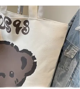 Close-up of cream canvas tote bag featuring a cartoon bear print and soft fabric texture
