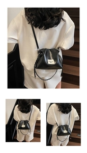 Close-up of black drawstring bucket bag with decorative woven chain strap and fabric label