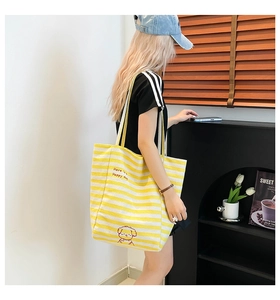 Détail du sac cabas en toile rayée avec illustration de chien mignon et logo texte