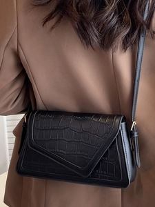 Fashionable black faux crocodile shoulder bag with flap closure on brown blazer model
