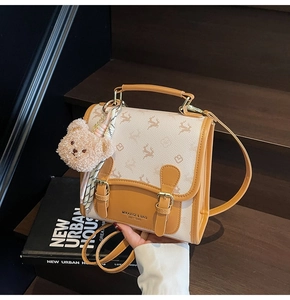 Détail d'un sac à dos rétro avec imprimé cerf, boucles en cuir et charm d'ours