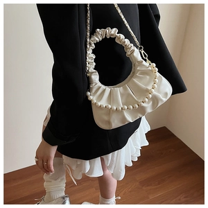 Detail of white ruched cloud bag featuring oversized pearl handle and gold chain strap