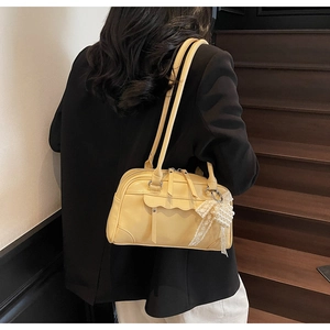 Détail du sac à main boston jaune clair avec breloque perle et bordure ondulée