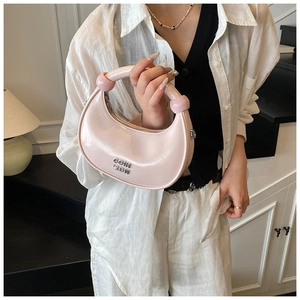 Detail of light pink crescent moon handbag with silver logo and chunky handle design