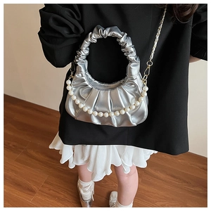 Detail of silver pleated cloud bag with pearl chain and metallic finish shown on model