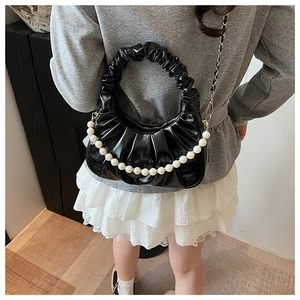 Detail of black pleated cloud bag with elegant large pearl chain and gold strap