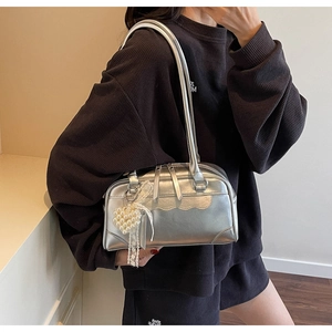Détail du sac cabas argenté avec breloque cœur en perle et accessoire à pompon