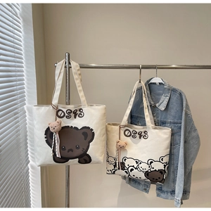 Detailed close-up of cream canvas tote bags featuring cute bear prints and plush charms