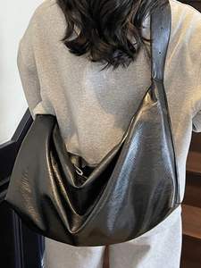 Minimalist black oil wax leather hobo bag with wide shoulder strap on model back view