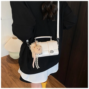 Detail of off-white crocodile embossed crossbody bag with plush bear charm and lock