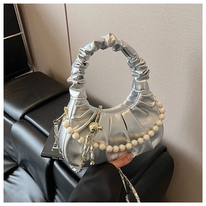 Detail view of silver pleated cloud bag with pearl strap and metal chain detail