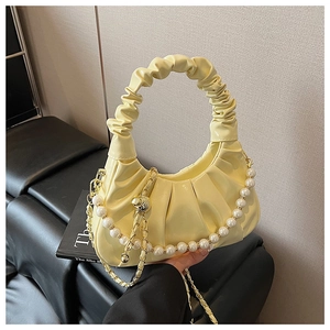 Detail of creamy yellow pleated cloud bag with large pearl chain and metallic sphere charm