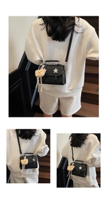 Detail view of black pebble leather crossbody bag with silver star and bear charm