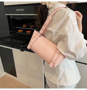 Détail d'un sac sous le bras rose avec œillets métalliques argentés et sangle à boucle décorative