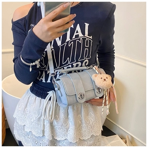 Detail of light blue faux crocodile leather crossbody bag with a plush bear charm