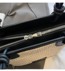 Dettaglio borsa in paglia beige con finiture in pelle nera e cerniera metallica argentata fluida