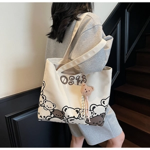 Detail of canvas tote bag featuring cute cartoon bear print and brown plush charm