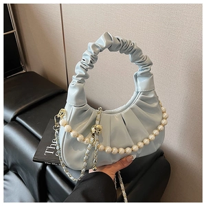 Detail of light blue ruched cloud bag featuring elegant pearl and metal chain strap