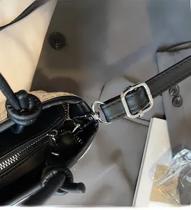 Dettaglio della borsa da spiaggia in paglia con finiture in pelle nera e fibbie