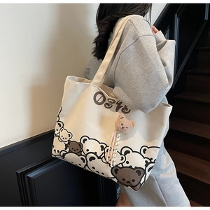 Detail of canvas tote bag featuring cute cartoon bear prints and plush mascot attachment