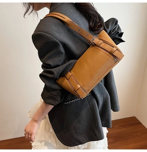 Détail du sac baguette en cuir marron caramel avec boucle rétro porté par un mannequin femme