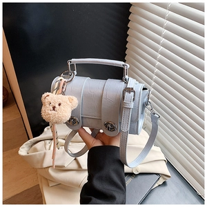 Detail of light blue crocodile embossed bag with twist lock and bear charm