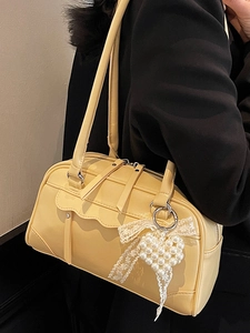 Sac Boston jaune crème avec nœud en dentelle et pendentif cœur perle porté par mannequin