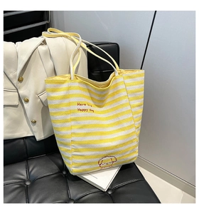 Détail du sac cabas en toile à rayures jaunes et blanches avec broderie chien sur une chaise
