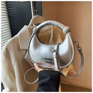 Detailed macro view of the silver crescent bag with metallic leather and branded lettering