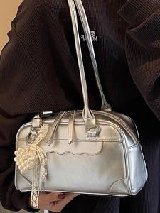 Sac à main Boston argenté métallisé avec breloque perle et dentelle porté par un mannequin