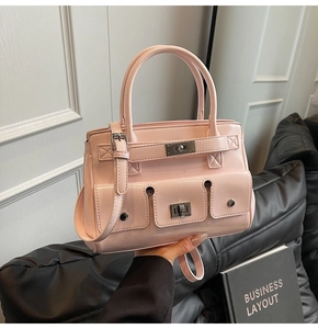 Close-up of pink patent leather handbag with metal turn-lock closure and functional pockets