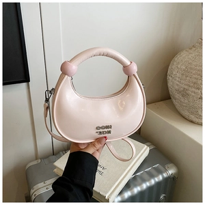 Detail of light pink crescent handbag with silver logo and round handle accents