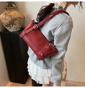 Détail d'un sac sous les aisselles en cuir rouge foncé avec sangles à boucles argentées