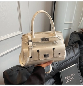 Detail showing the triple front pockets with silver buckles on the off-white leather tote bag