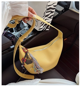 Détail du sac hobo en cuir jaune avec pompon coloré et fermeture éclair métallique