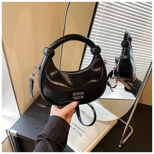 Detail view of black glossy crescent bag with silver COIN 2DN logo and knotted handle