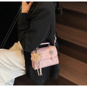 Detail of pink faux leather crossbody bag with star stud and brown plush bear charm