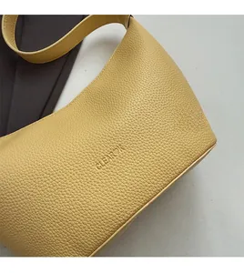 Gros plan du sac en cuir grainé jaune avec le logo gaufré CLEAR OK sur la texture riche