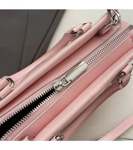Close-up of smooth silver zipper and double handles on a pink leather tote bag
