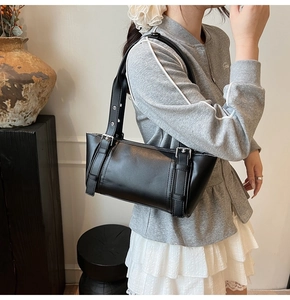 Détail du sac sous le bras noir avec double bandoulière et boucles de réglage en métal