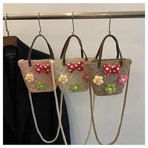 Detail view of woven straw bags featuring handmade 3D floral accents and polka dot bows
