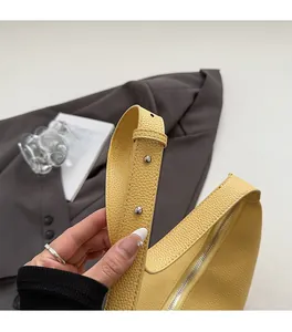 Détail d'un sac jaune en cuir grainé avec rivets argentés et bandoulière large