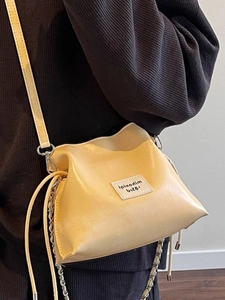 Minimalist beige drawstring shell crossbody bag with soft leather and silver chain strap