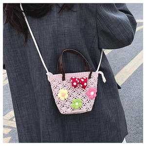 Detail of pink hand-crocheted bag featuring floral 3D accents and a red polka dot bow