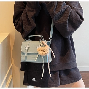 Blue textured leather crossbody bag with silver stars and plush bear charm on model
